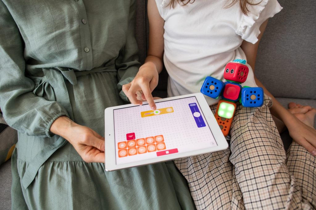 Toys to learn programming: mother and child on a tablet playing a programming game