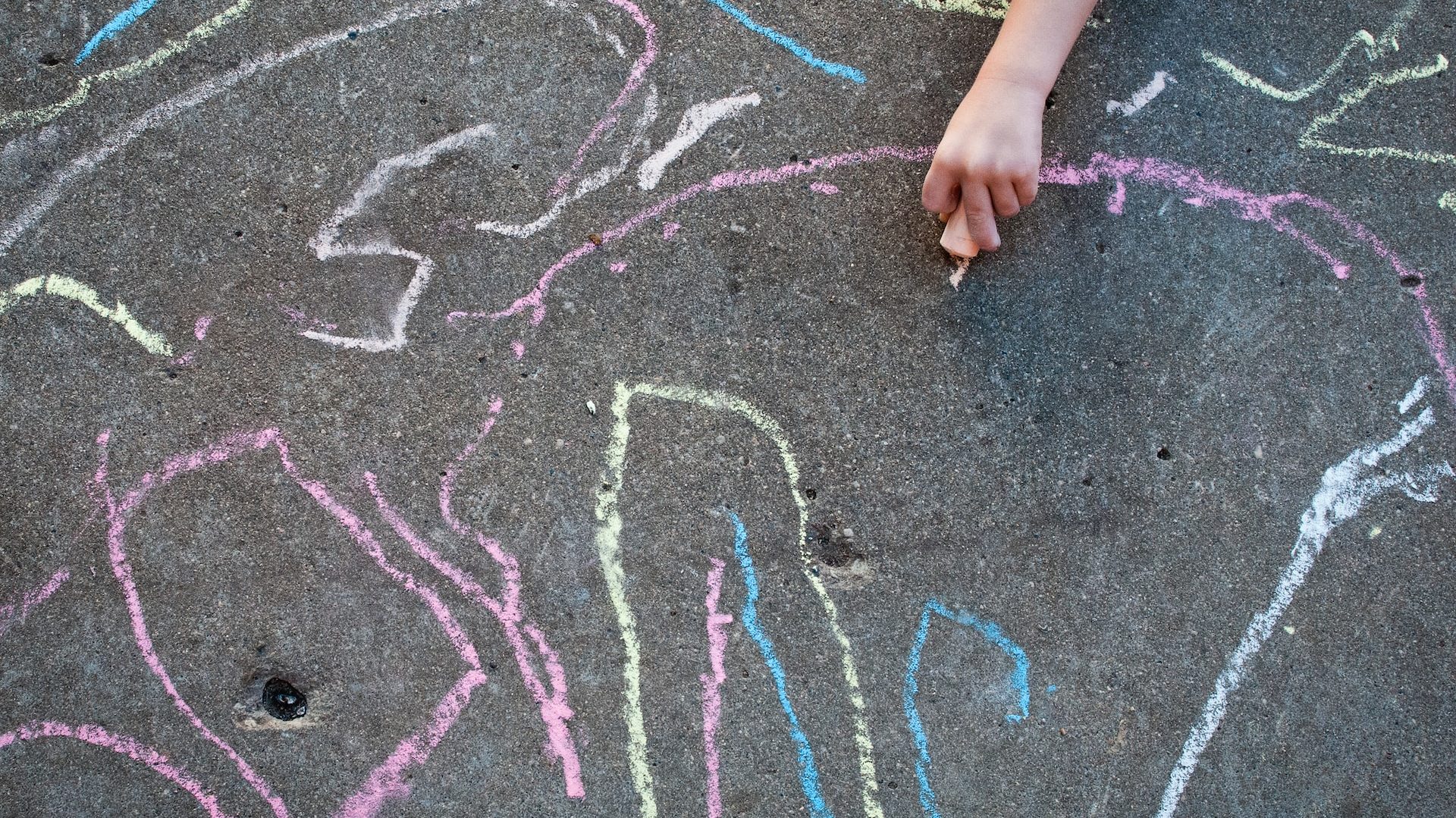 Child drawing sidewalk chalk boosting creativity.